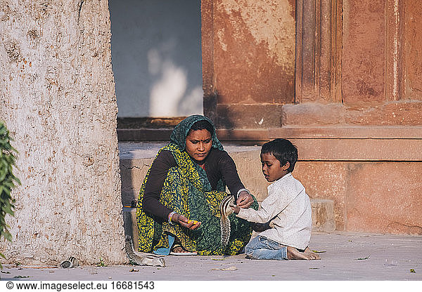 Indian woman and her son feeding a couple squirrel by the Agra fort.