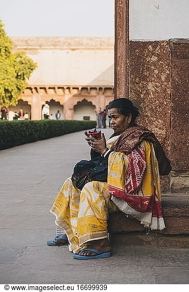 Indian woman playing with toy camera dressed in yellow sari at the Agra Fort Entrance.