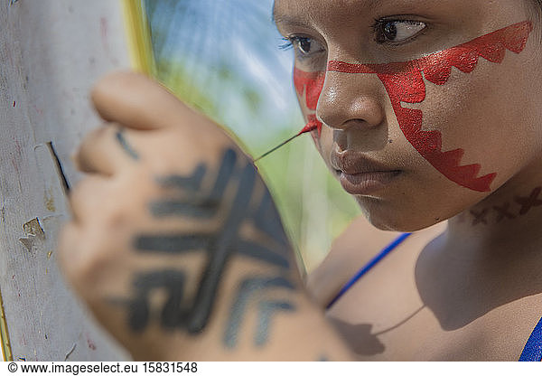 Indigene Frau bemalt ihr Gesicht im Dorf Dessana