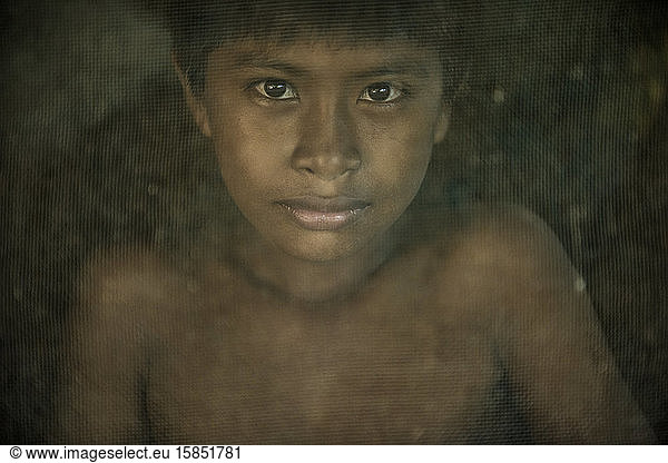Indigener Junge hinter Moskitonetz im Dorf Dessana