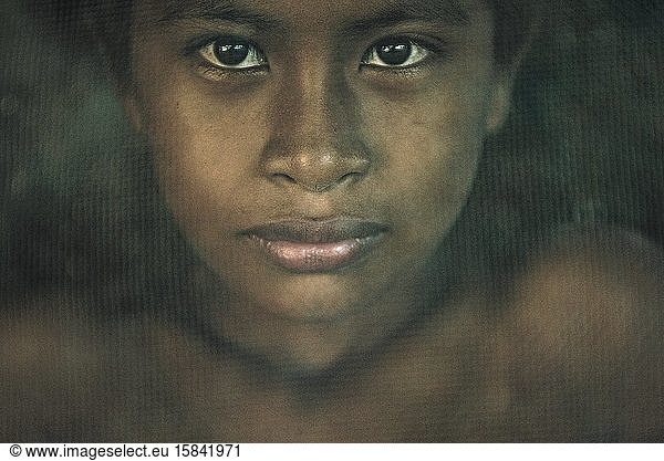 Indigenous boy behind mosquito net at Dessana Village