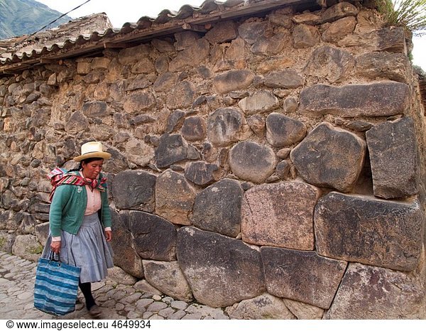 Indigenous woman walking along cobblestone street