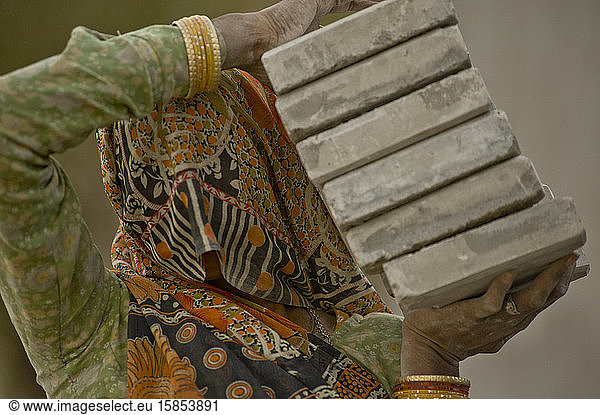 Indische Arbeiterin trägt schweres Baumaterial
