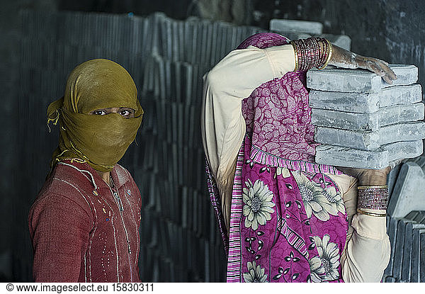 Indische Arbeiterinnen  die schweres Baumaterial tragen