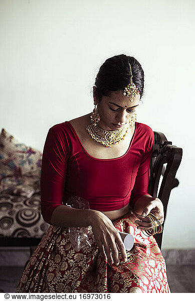 Indische Braut bereitet sich auf traditionelle indische Hochzeit mit rotem Sari vor