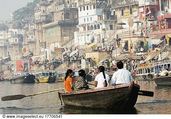 Indische Familie  die den heiligen  aber verschmutzten Fluss Ganges entlang rudert  vorbei an badenden Ghats; Uttar Pradesh  Indien