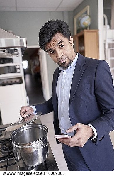 Indischer Geschäftsmann bereit zum Kochen mit Smartphone in der Hand