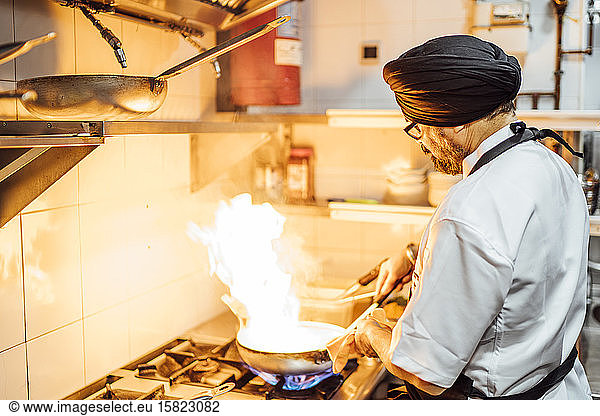 Indischer Koch brennt Essen in Restaurantküche an