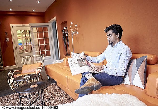 Indischer Mann liest Zeitung in der Lobby