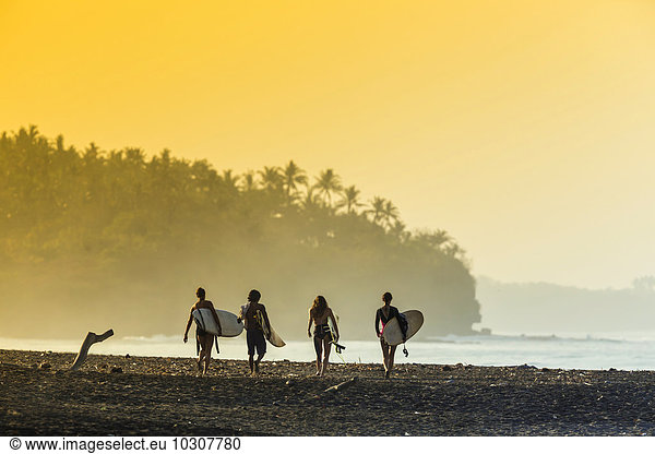 Indonesia,  Bali,  surfers on beach in the morning light