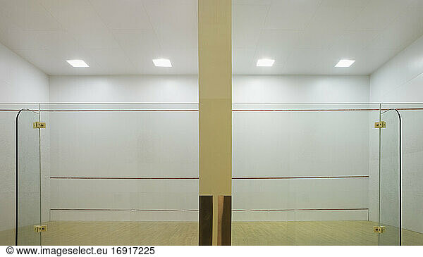 Indoor squash court with glass walls and markings.