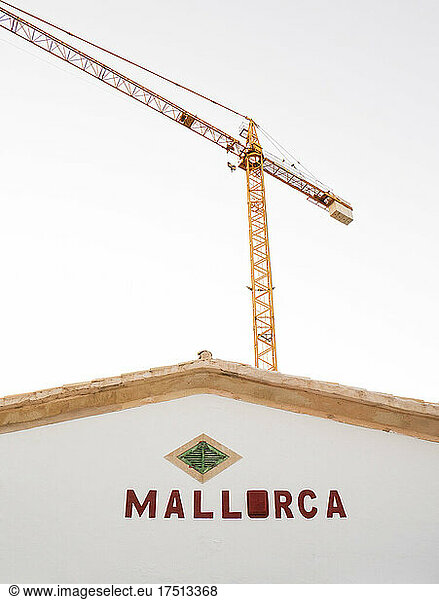 Industrial crane looming against clear sky behind house in Mallorca
