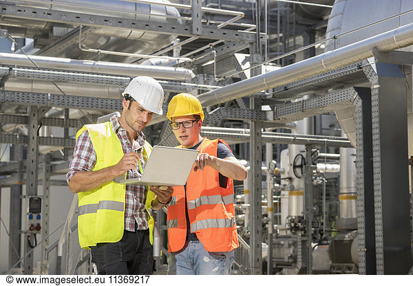 Ingenieur mit seinem Kollegen bei einer Besprechung mit Laptop im geothermischen Kraftwerk