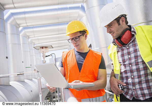 Ingenieur und Arbeiter in einer Besprechung mit Laptop im geothermischen Kraftwerk