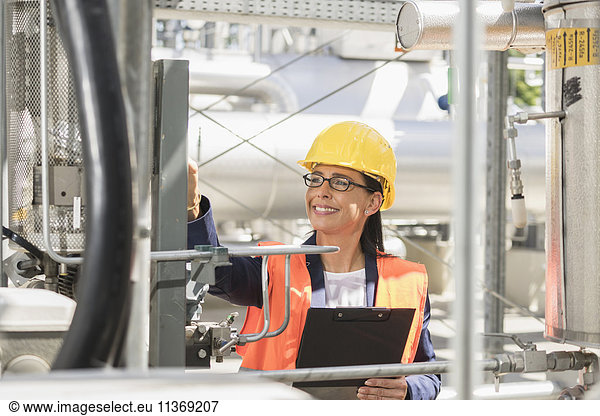 Ingenieurin lächelt mit einem Dokument in einem geothermischen Kraftwerk