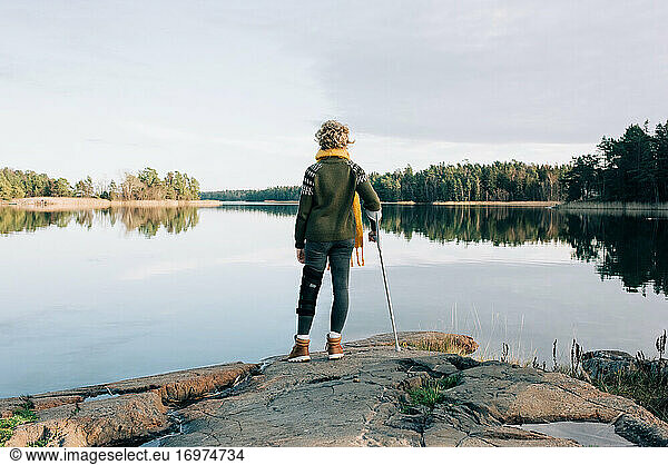 injured woman stood at the waters edge looking at the beautiful view