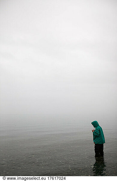 Inmitten von dichtem Nebel steht ein junges Mädchen im seichten Wasser; Inside Passage  Alaska