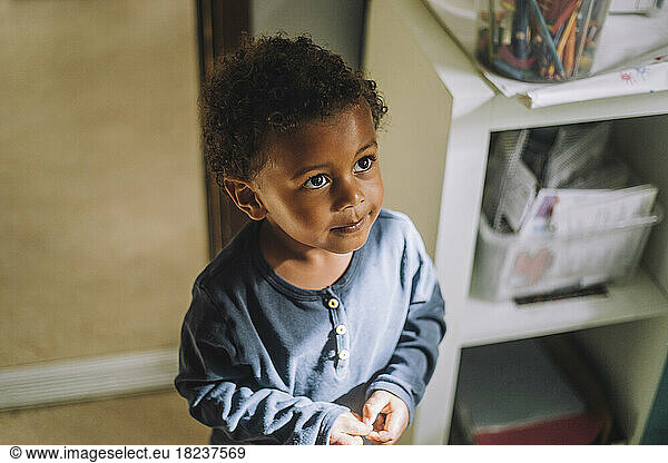 Innocent boy looking up while standing in day care center