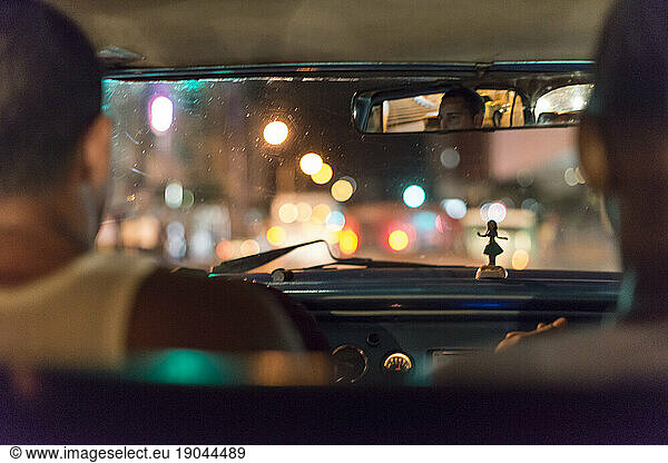 Inside a Cuban taxi at night. Colorful lights glow outside  hula doll on dashboard. Havana  La Habana  Cuba