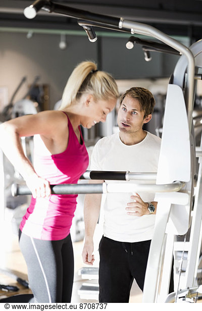 Instructor motivating customer exercising at gym
