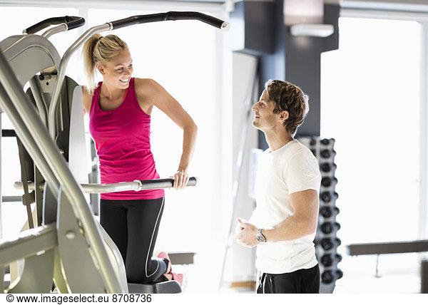 Instructor talking to customer exercising at gym