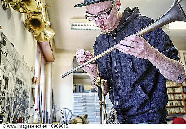 Instrument maker making trumpet in workshop