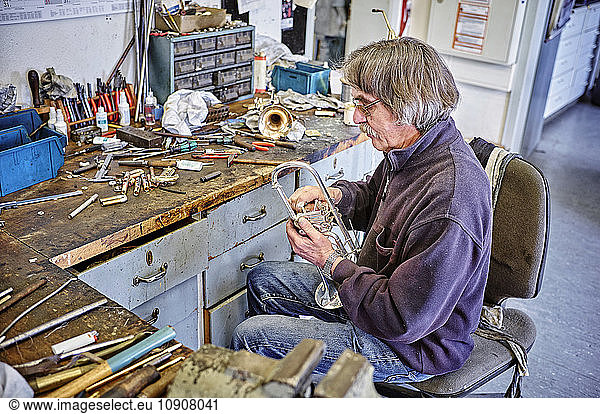 Instrument maker repairing trumpet in workshop
