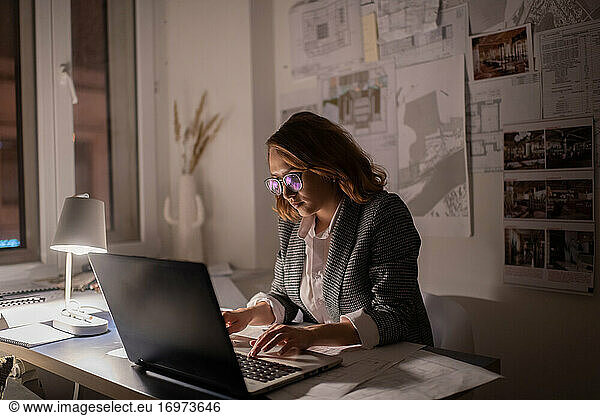 Intelligente Geschäftsfrau mit Laptop in einem dunklen Büro