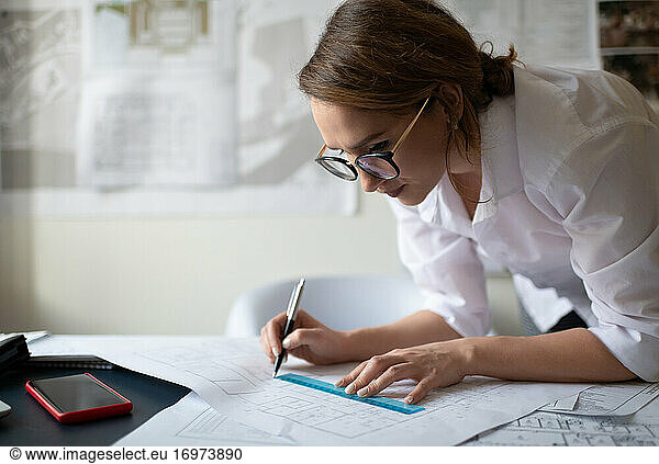 Intelligente Geschäftsfrau zeichnet Blaupause im Büro