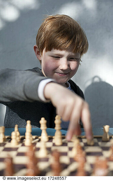 Intelligenter Junge spielt Schach vor einer Wand