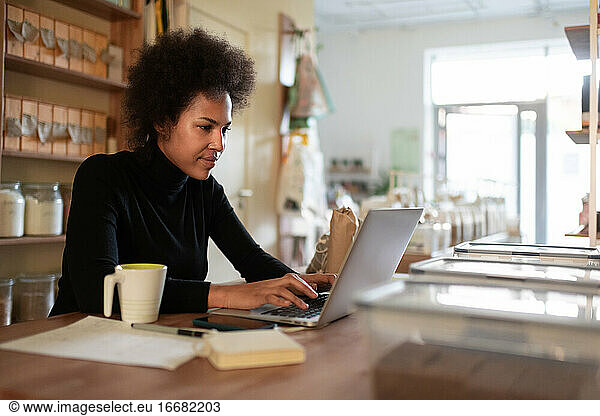 Intelligenter schwarzer Unternehmer mit Laptop im Geschäft