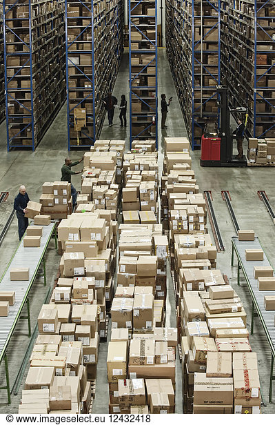 Interior view of a large distribution warehouse with product's in cardboard boxes stacked on pallets and large storage racks.