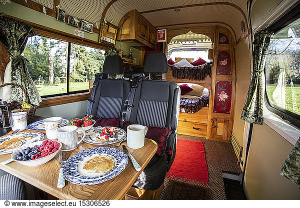Interior view of camper van with breakfast on table.