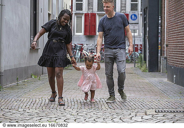 Interracial couple teaching their toddler to walk