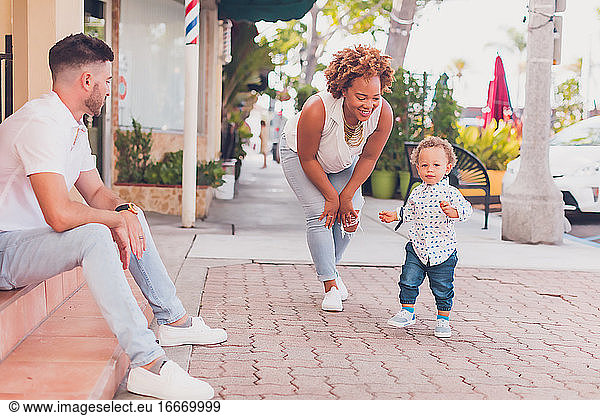 Interracial family playing with toddler on the sidewalk