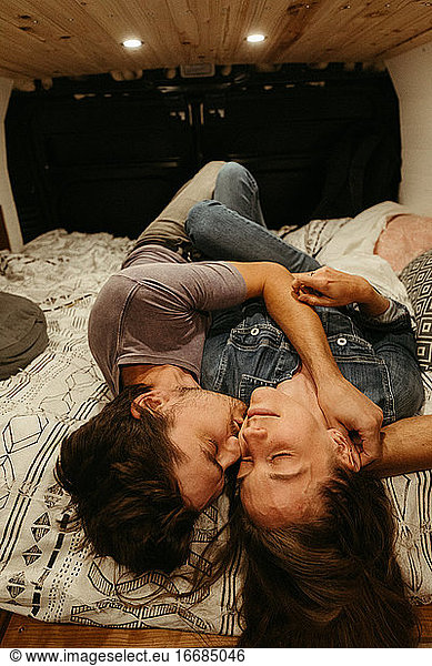 intimate moment as newly engaged couple lay on bed together for kiss