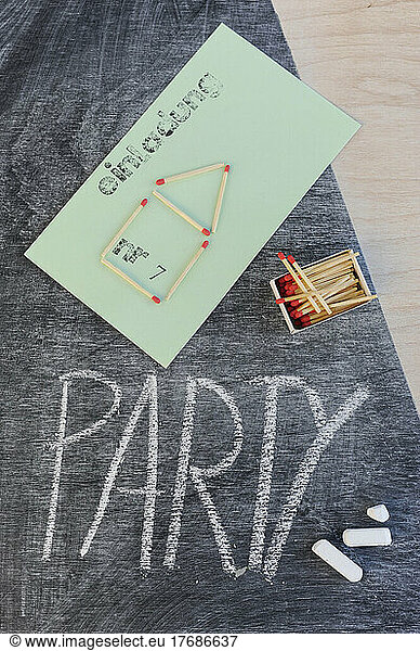 Invitation card with matchstick home design by party text on blackboard