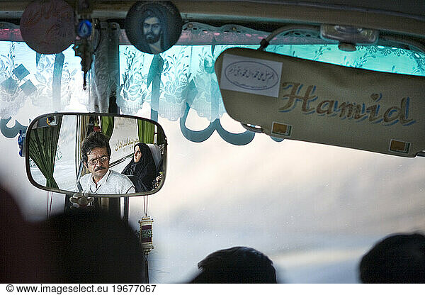Iranian bus driver reflected in rearview mirror in Dasht e Kavir  Iran.