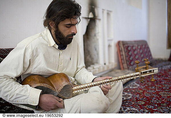 Iranian man playing traditional string instrument in Garmeh  Iran.