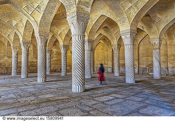 Iranische Frau geht durch die Gebetshalle mit Shabestan-Säulen  Vakil-Moschee  Shiraz  Provinz Fars  Iran  Asien