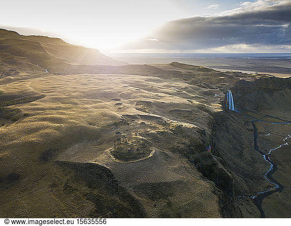 Island  Luftaufnahme eines Wasserfalls  der bei Sonnenuntergang von einer hohen Klippe herunterplätschert