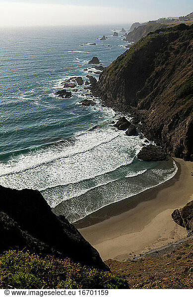 Isolated cove with waves from ocean and golden sand in California