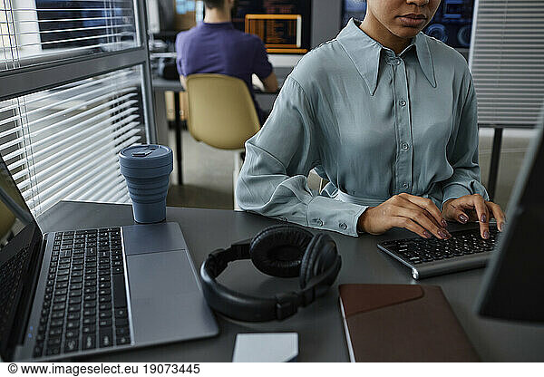 IT professional typing on keyboard with colleague in background
