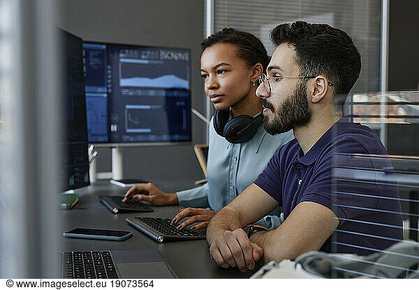 IT professionals working together on computers at desk