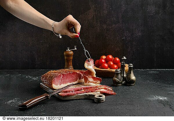 Italian dry-cured ham prosciutto on wooden cutting board