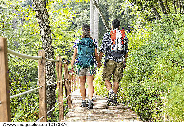 Italien  Massa  Rückansicht eines jungen Paares beim Wandern und Spazierengehen auf einer Strandpromenade in den Alpi Apuane