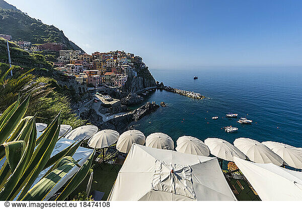 Italy  Liguria  Manarola  View of historic village along Cinque Terre with row of beach umbrellas in foreground
