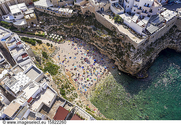 Italy  Polignano a Mare  Aerial view of crowd of people relaxing on sandy beach of coastal town in summer