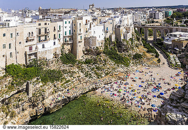 Italy  Polignano a Mare  Aerial view of crowd of people relaxing on sandy beach of coastal town in summer