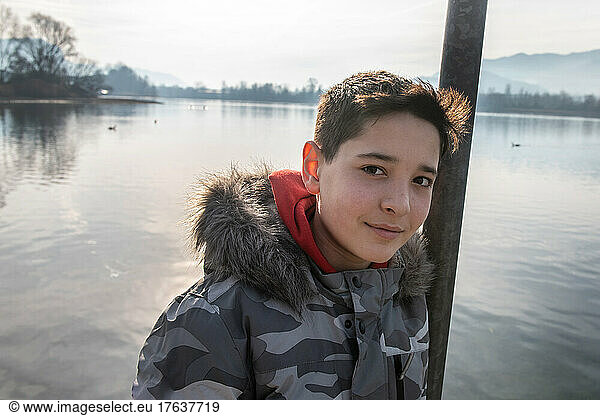 Italy  Portrait of smiling boy  by calm lake